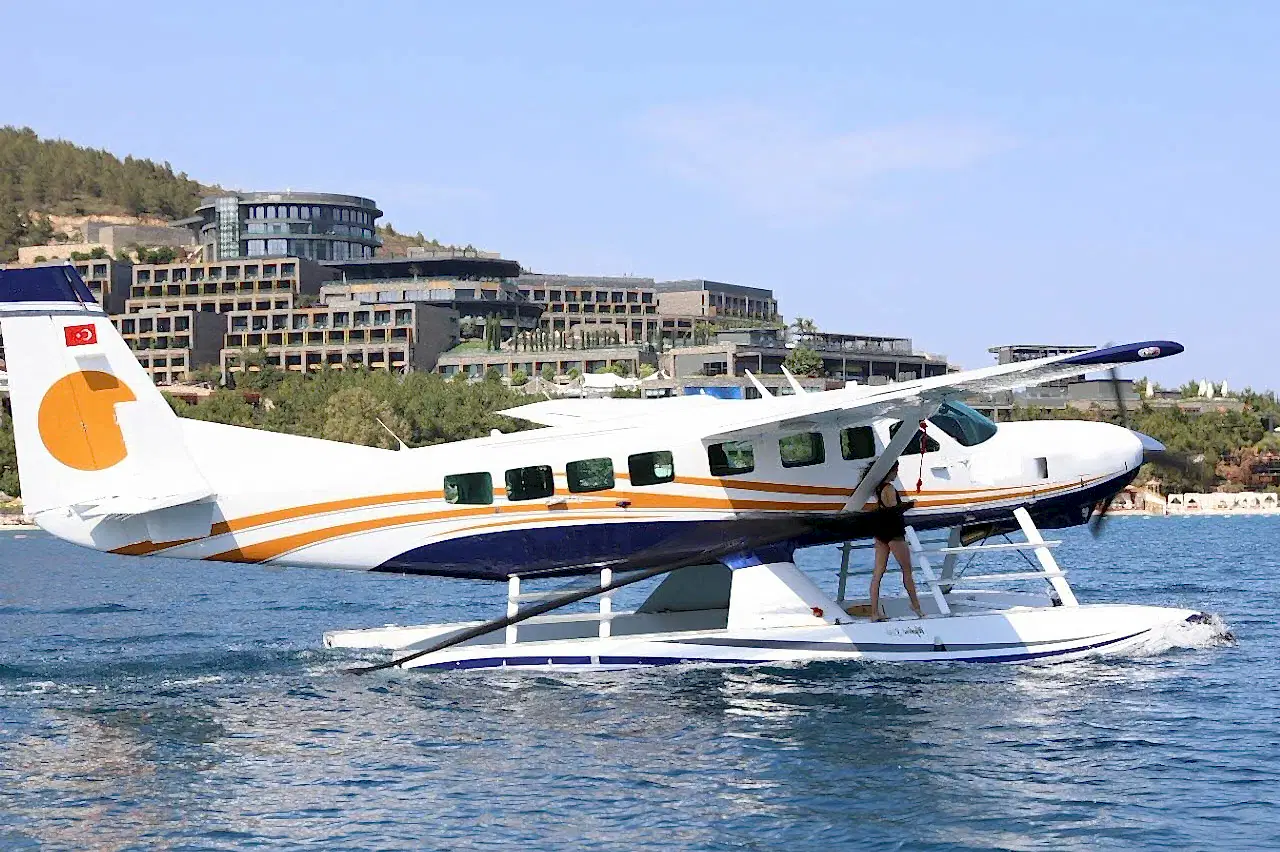 Model passenger enjoying Antalya seaplane transfer with stunning beach views in the background.