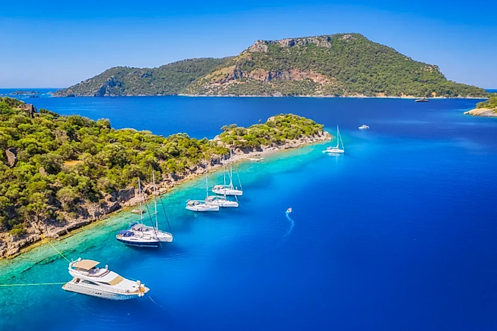 Aerial view of Fethiye’s turquoise coastline, sandy beaches, and lush hills during a helicopter transfer from Antalya
